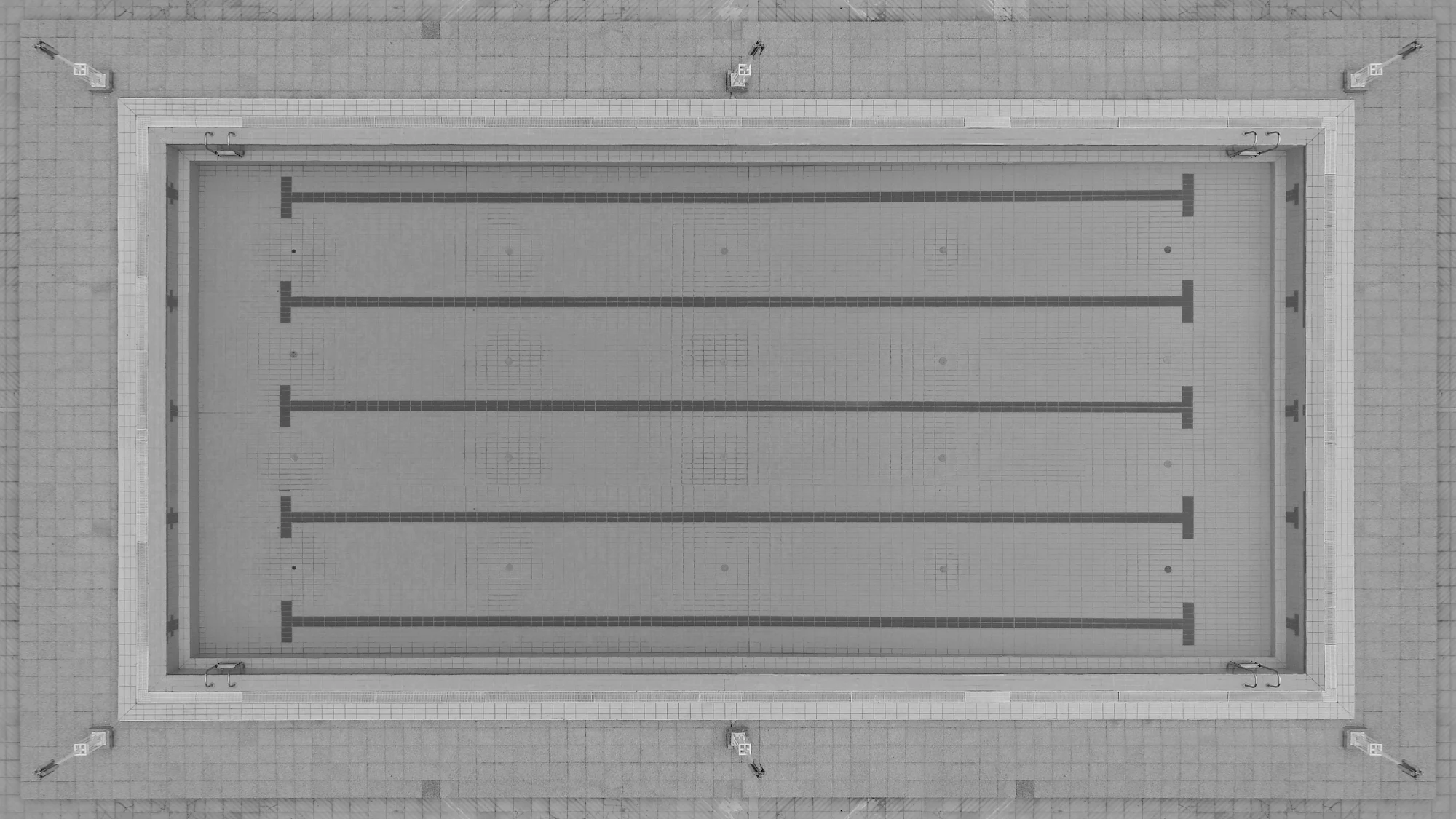 An empty competition pool with five lane ropes, seen from directly above, in black and white