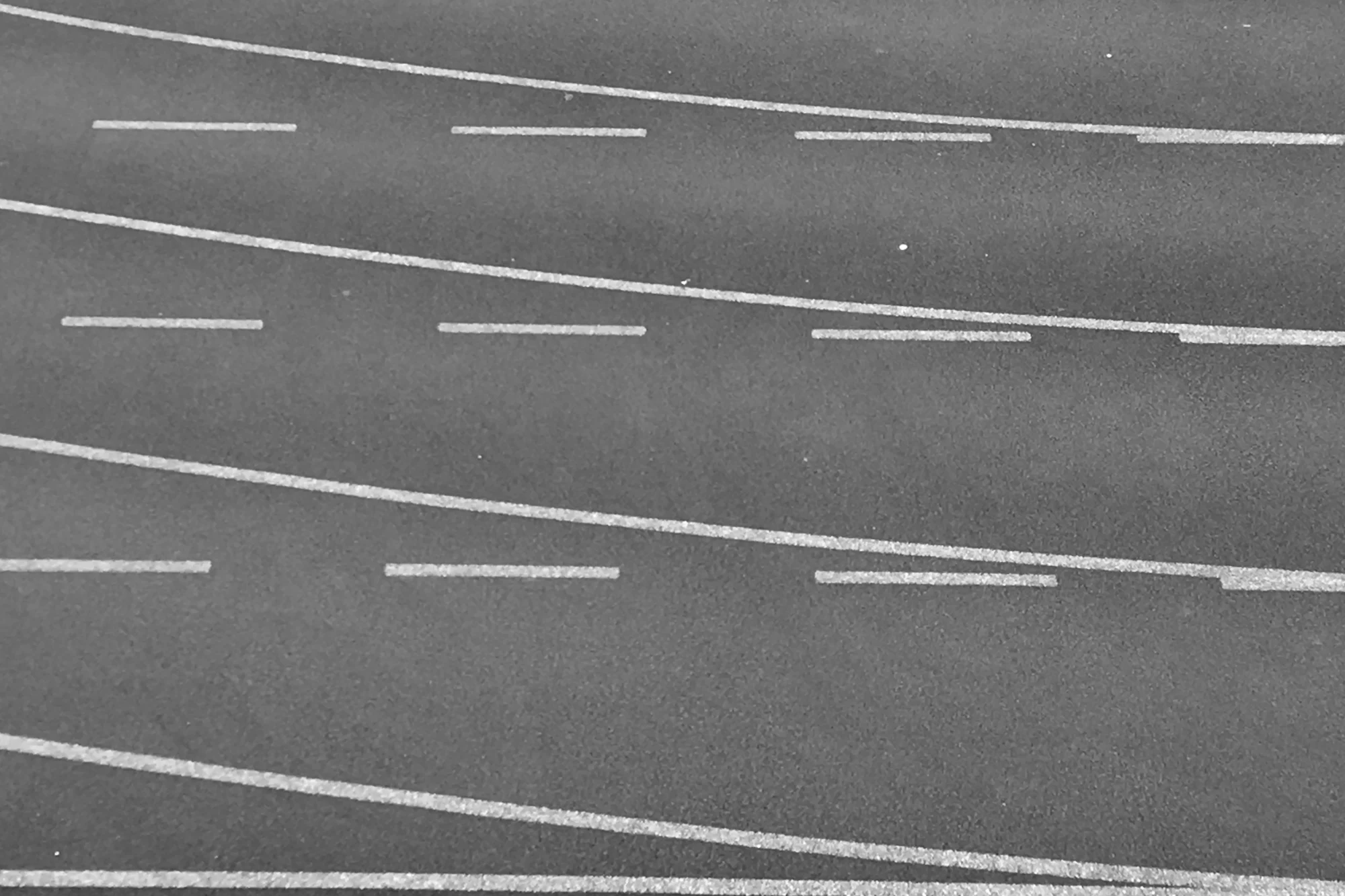 Curved lanes of a running track, seen from above, in black and white